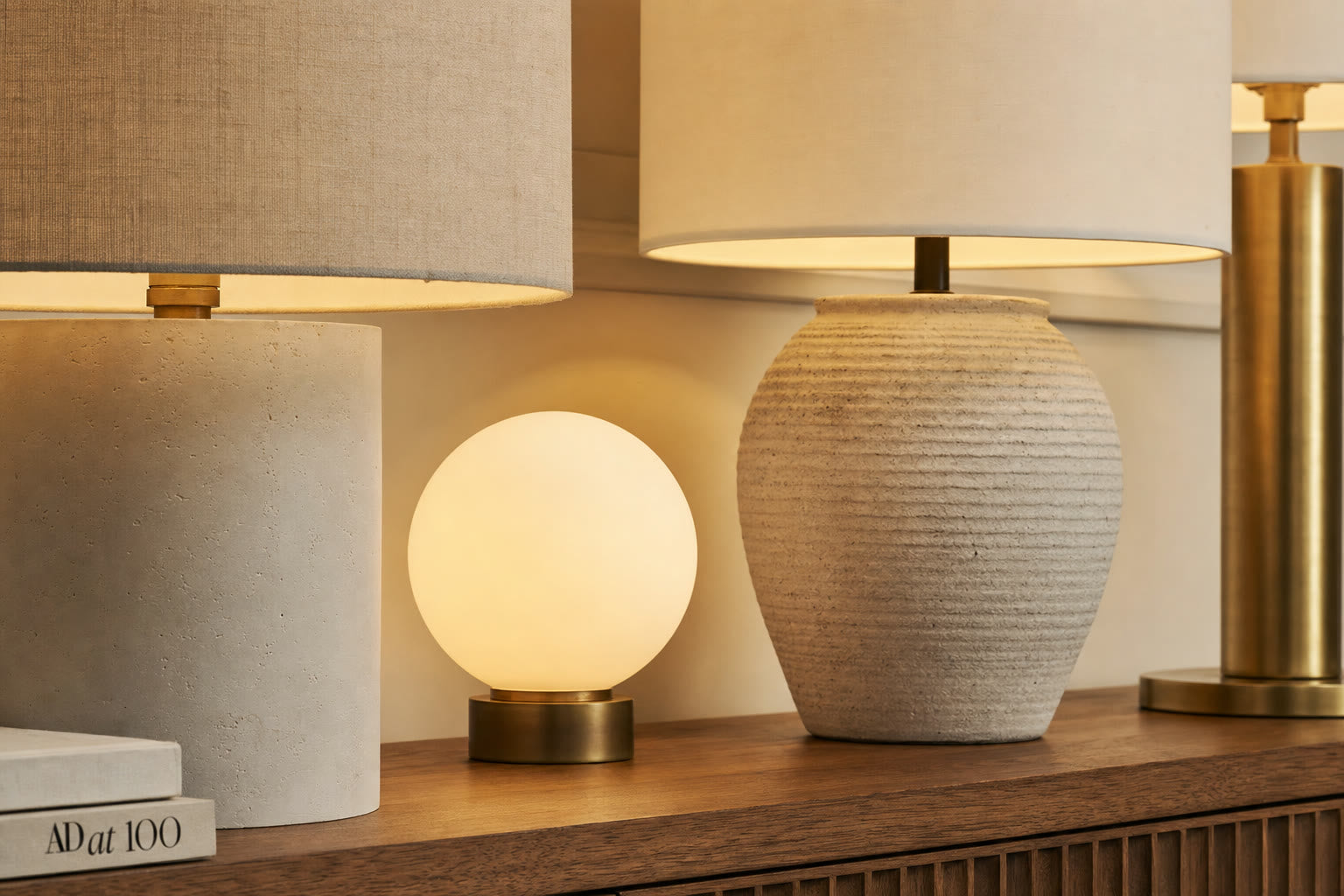 A close-up of linen, opal glass, and ceramic lamp shades catching warm light